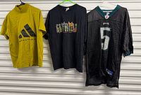 Three shirts hanging: Adidas tee, graphic tee, Eagles jersey