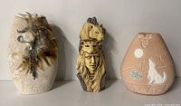 Three items side by side: off-white textured vase with feathers, carved figurine, terracotta wolf vase