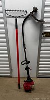 Full view of both garden tools—rake and string trimmer—standing upright