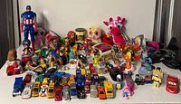 Full lot view showing action figures, plush toys, die-cast cars and small figurines