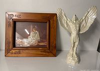 Wood frame with print and ceramic winged figurine side by side