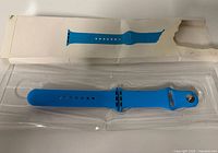 Blue Apple Watch sport band in clear tray with torn outer box