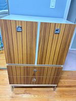 Full frontal view showing cabinet doors, drawers, chrome hardware and legs