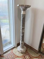 Full view of marble pedestal standing in corner