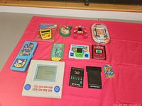 Group shot of all handheld games and toys on pink cloth