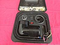 Compressor, gauge, hose and power cord inside open carrying case