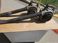 Two gas leaf blowers side by side on table showing overall form and taped tube