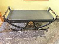Full view of metal bench showing curved legs and cushion