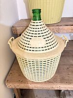 Demijohn inside yellow plastic basket with lid and handles