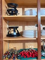 Shelf with black burner stands, ceramic bowls, plates, skewers