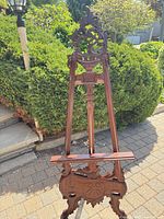 Front view of carved mahogany easel showing scrollwork crest and support ledge
