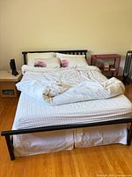 Full view of assembled queen bed frame with mattress showing black metal headboard, side and foot rails
