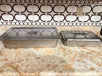 Two stainless lasagna pans with lids on countertop