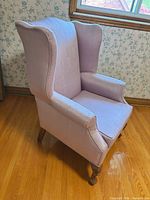 Front angled view of pink wingback armchair showing overall style and upholstery