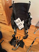 Front view of wheelchair with footrests detached and manual resting on seat