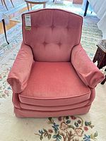 Front view of pink velvet armchair with tufted back and skirted base