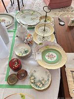 overview showing teapot, three-tier stand, stack of plates, larger platters, red box, brass and stoneware dishes