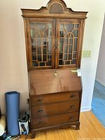Front view of entire secretary desk showing bookcase top, drop front, and three drawers