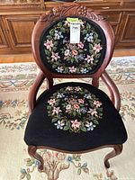 Front view showing carved wood frame, floral needlepoint back and seat