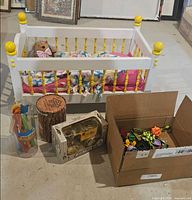 Overall lot view showing doll bed, DIY kit cylinder, die-cast Ford bank, clear toy tube and box of toys