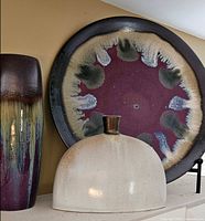 Group shot showing all three pottery pieces: charger plate, tall vase, cream vase