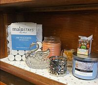 Group view of tealight pack, swan dish, peach jar candle, gold votive, filigree holder, owl candle and large blue jar candle