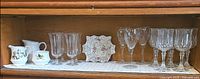 Shelf view showing entire lot: china creamer, sugar bowl, chintz dish, crystal glasses