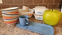 Full lot showing casseroles, bowls, melamine pieces, decorative apple