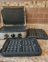 Griddler open with installed grill plates and waffle plates beside
