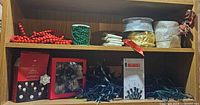 Overall view of shelves showing bead garlands, candles, ribbon rolls, boxed lights and loose light string