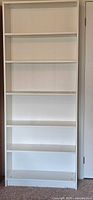 Front view of tall white shelving unit with six shelves