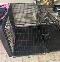 Front view of large black wire dog crate showing door and plastic floor tray