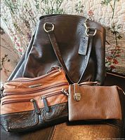 Three brown leather purses together showing relative sizes and colors