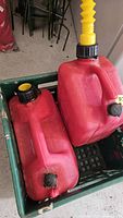 two large red fuel cans in crate showing caps and spout