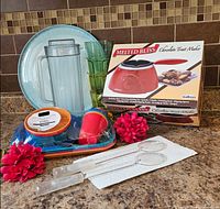 All items displayed on countertop including trays, pitcher, tumblers, children’s plates, salad servers and boxed Salton chocolate maker