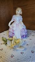 Royal Doulton figurine and porcelain rose on textile surface