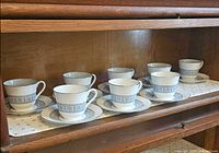 Full set of 8 teacups and 8 saucers displayed in cabinet