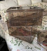 two smoked clear plastic storage boxes stacked on bed