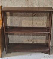 Front view of small wooden bookcase showing two shelves and wear