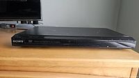 Front view of slim black Sony DVD CD player showing brand logo and disc tray