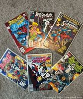 All six comic books fanned out on floor, covers visible