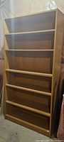 Front view of tall oak-finish bookcase with six shelves