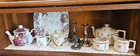 Cabinet view displaying both teapots, matching cream & sugar, cookie plate, three candlesticks