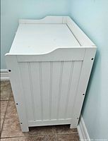 Left side view of white storage bench showing panelled side and curved rail