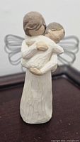 Front view of figurine showing adult angel cradling child