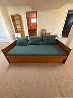 Front view of daybed showing wood-tone frame, seat cushion, back cushions and trundle drawer