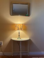 Table, lamp, and mirror displayed together