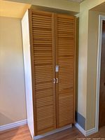 Full view of wardrobe front showing louvered doors and handles