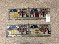 Both stained glass panels laid flat on carpet showing full designs and ruler for scale