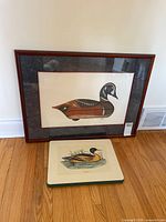 Both duck artworks: framed Harlequin Drake Decoy II print positioned behind smaller wood panel print